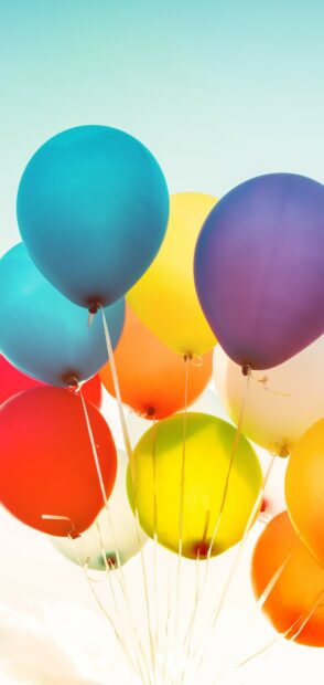 Colorful balloons floating upwards under a clear sky