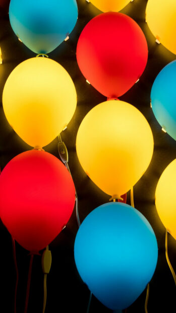 Colorful balloons glowing in red yellow and blue colors arranged against a dark background