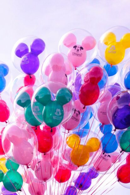 Colorful balloons shaped like Mickey ears floating in the sky with vibrant colors