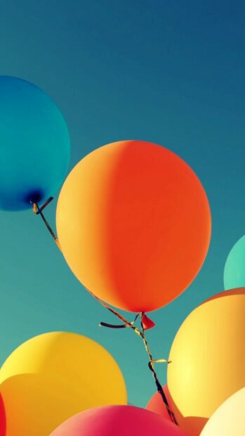 Colorful balloons floating against a clear blue sky in vibrant hues