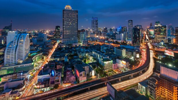 A vibrant Bangkok skyline at night with busy highways and illuminated skyscrapers in the cityscape