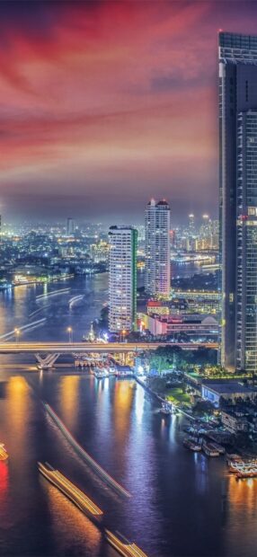 Night view of Bangkok skyline with river and city lights in a vibrant sky