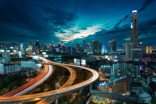 Busy Bangkok city skyline at night with vibrant lights and clear sky