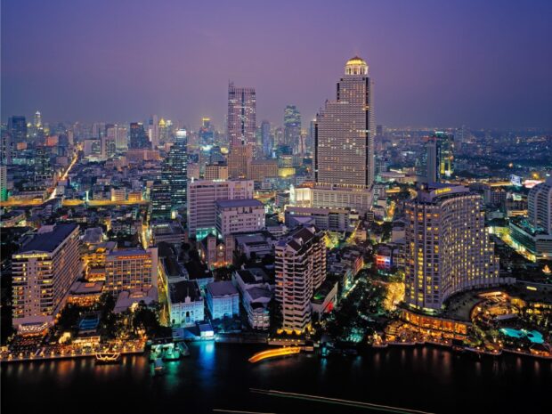 Night view of the Bangkok skyline with illuminated buildings and the riverfront