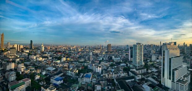 Panoramic view of Bangkok skyline with tall buildings under a blue sky in the evening