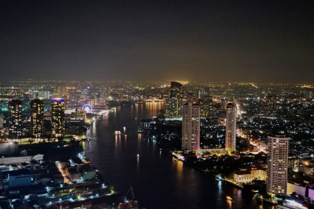 Night view of Bangkok skyline featuring river and illuminated skyscrapers at night
