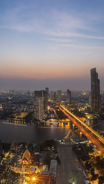Evening view of Bangkok skyline with river and illuminated buildings at dusk