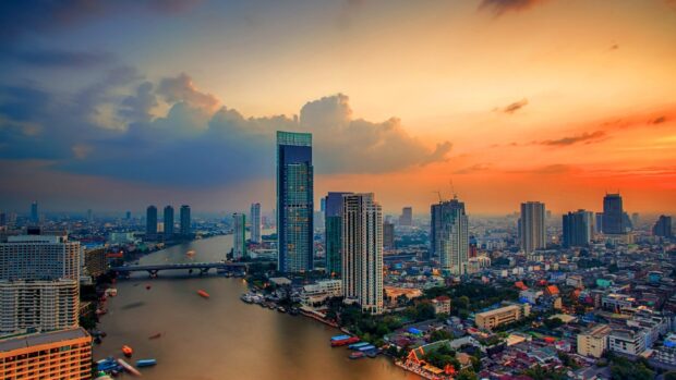 Bangkok city skyline at sunset with river and tall buildings in vibrant colors
