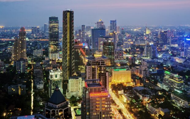 Nighttime cityscape of Bangkok with illuminated skyscrapers and traffic lights