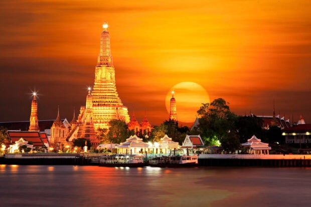 Stunning sunset view of Bangkok temple architecture with vibrant orange sky
