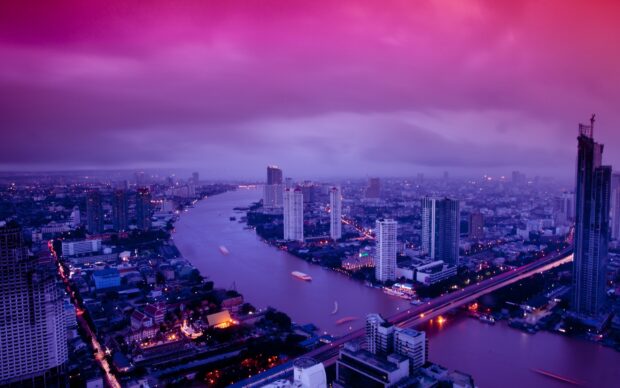 Twilight cityscape of Bangkok river with skyscrapers and vibrant lights in evening sky