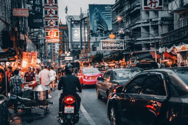 Busy street scene in Bangkok with motorcycles cars and pedestrians on crowded road