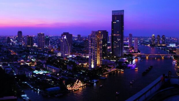Evening cityscape of Bangkok with river and illuminated buildings at dusk