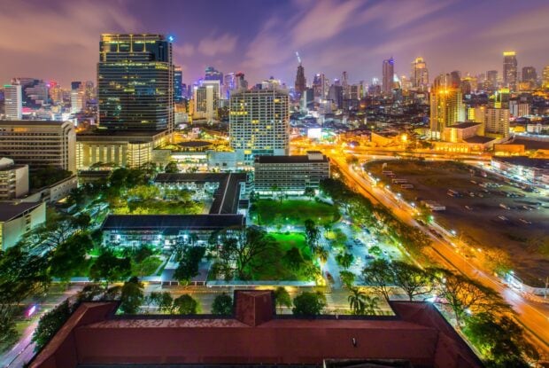 A vibrant view of Bangkok cityscape with illuminated buildings and green parks at night