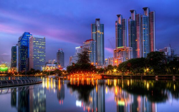 Modern Bangkok skyline with city lights reflecting on the river at dusk