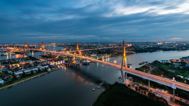 The cityscape of Bangkok with the illuminated bridge crossing the river at dusk