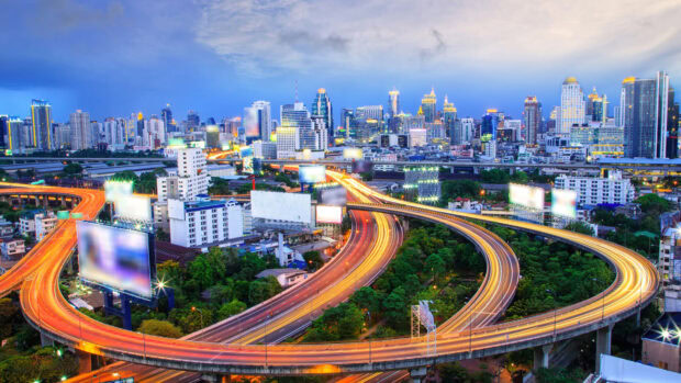 A vibrant Bangkok cityscape with highways and skyscrapers at dusk