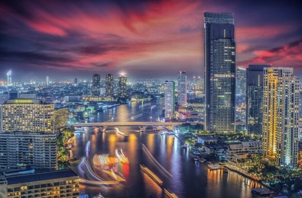 Bangkok cityscape with river and lit skyscrapers at sunset in Bangkok