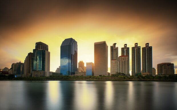 Modern Bangkok skyline during sunset with high rise buildings reflecting on water
