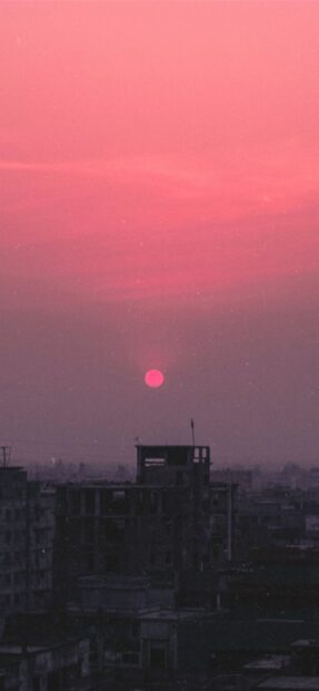 Pink sunset over Bangladesh cityscape at dusk with silhouetted buildings and vibrant sky