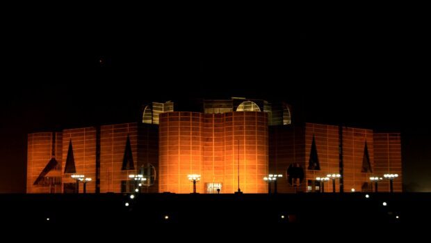 Night view of Bangladesh National Parliament building illuminated in vibrant orange