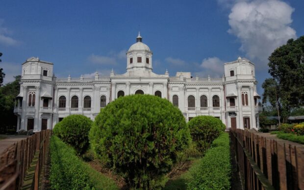 A historic building surrounded by green bushes representing Bangladesh