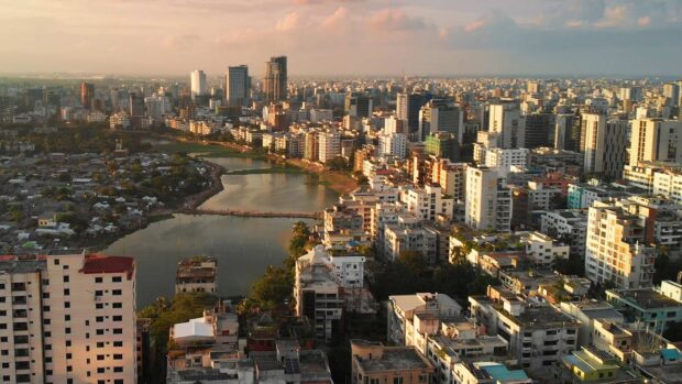 A scenic view of Bangladesh cityscape with river and high rise buildings at sunset