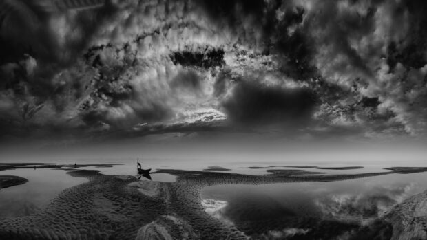 A fisherman navigating the calm waters in Bangladesh during a dramatic cloudy sky