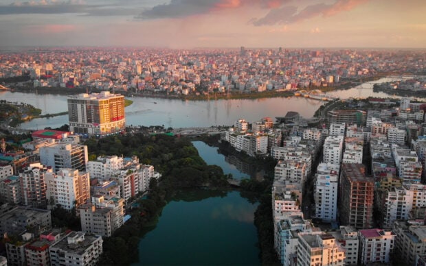 Aerial view of Bangladesh cityscape with rivers and high rise buildings at sunset