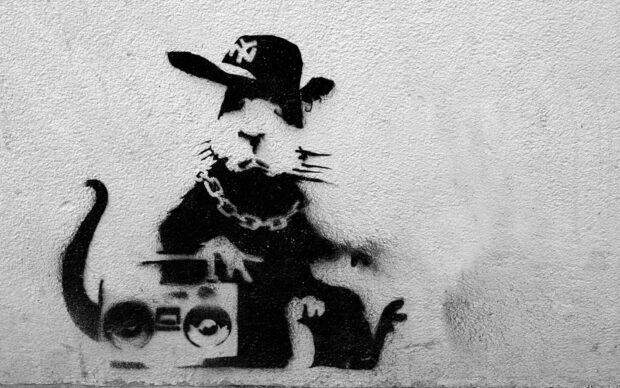 A Banksy graffiti art featuring a rat wearing a hat and chain with a boombox