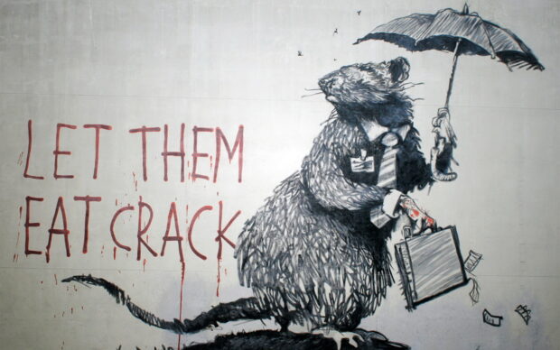 A Banksy rat holding an umbrella and briefcase with a message about addiction on a wall mural