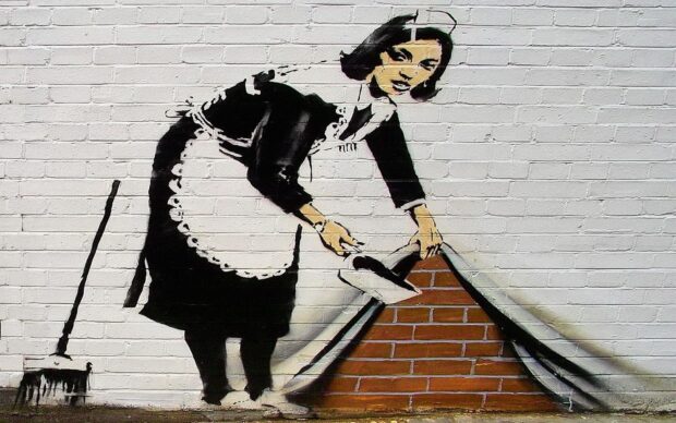 A Banksy artwork of a maid lifting a wall to reveal bricks underneath