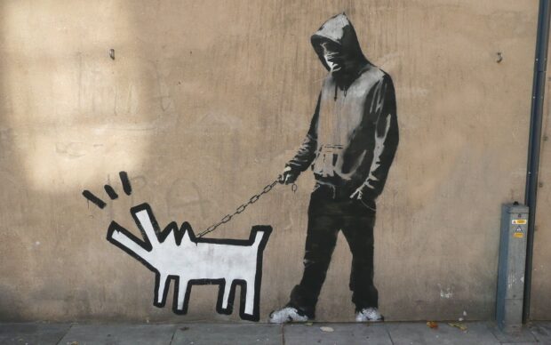 A street artwork showing a person in hooded clothing walking a stylized dog on a leash