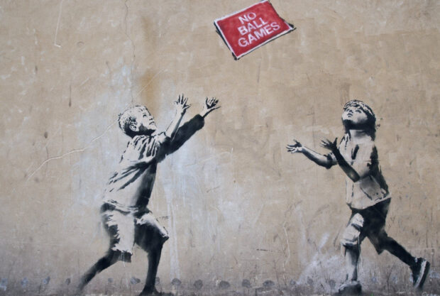 Two children reaching for a red no ball games sign street art graffiti