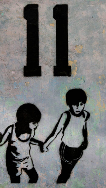 Two children holding hands stencil graffiti on textured wall with number eleven