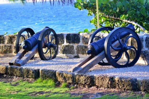 Black cannons on wooden mounts facing the ocean at a historic site in Barbados