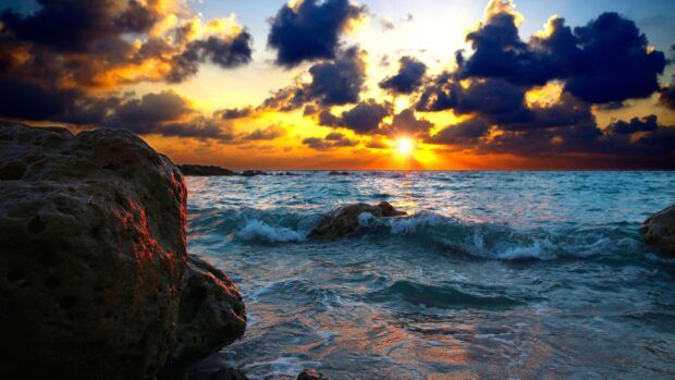 Sunset over Barbados ocean with rocks in foreground and dramatic clouds