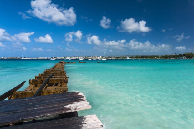Old wooden pier over turquoise sea in Barbados harbor