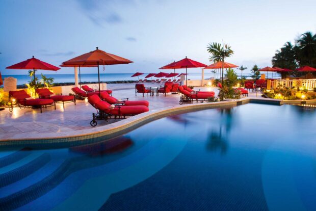 Relaxing outdoor lounge area in Barbados with red umbrellas and seating near a pool