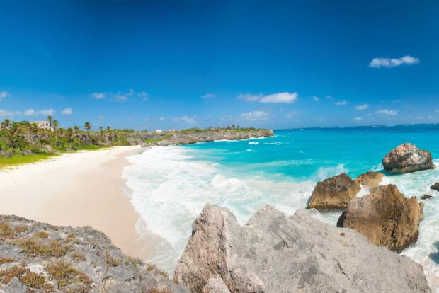 A scenic view of Barbados coastline with turquoise water and rocky shore under blue sky