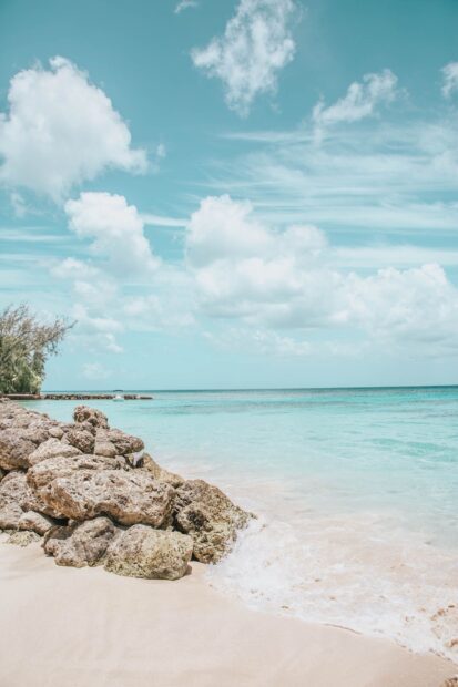 Rocky shore and turquoise sea in Barbados with clear sky and clouds
