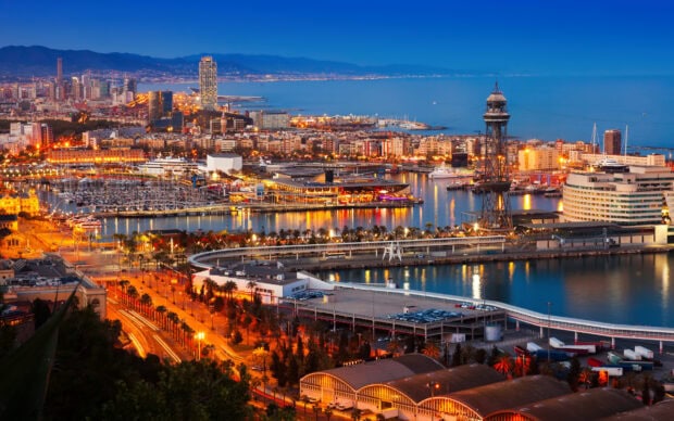 Evening view of Barcelona city skyline with ports and hills in the background