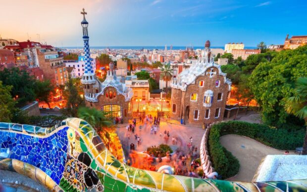 The vibrant cityscape of Barcelona with Gaudi architecture and colorful mosaic bench in the foreground