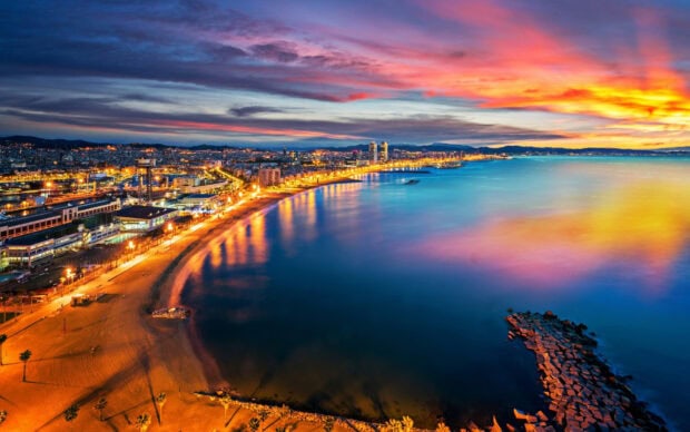 Vibrant Barcelona City coastline at sunset with colorful sky and illuminated buildings