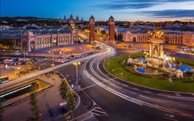 Barcelona city street view with famous towers and light trails at dusk