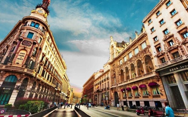 Historic buildings in Barcelona city center with a bright sky and bustling street