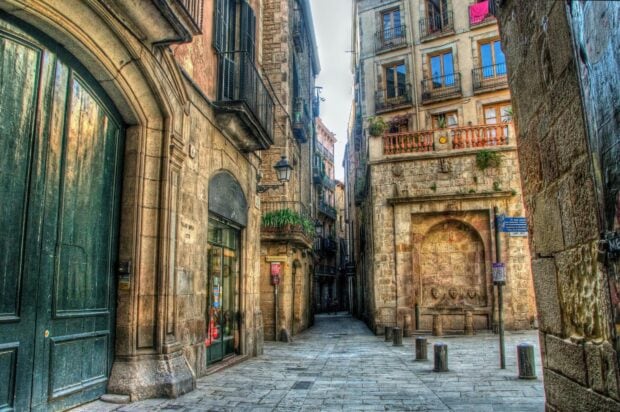 Narrow street scene in Barcelona city with old stone buildings and balconies
