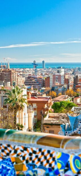 Colorful mosaic bench in a Barcelona city with cityscape and sea view in the background