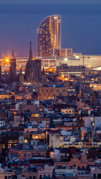 Night cityscape of Barcelona with illuminated buildings and the iconic W hotel tower