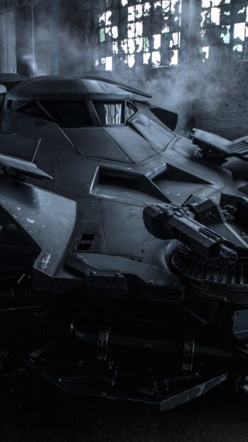 A detailed Batmobile design captured in a dark industrial setting with mist around the vehicle